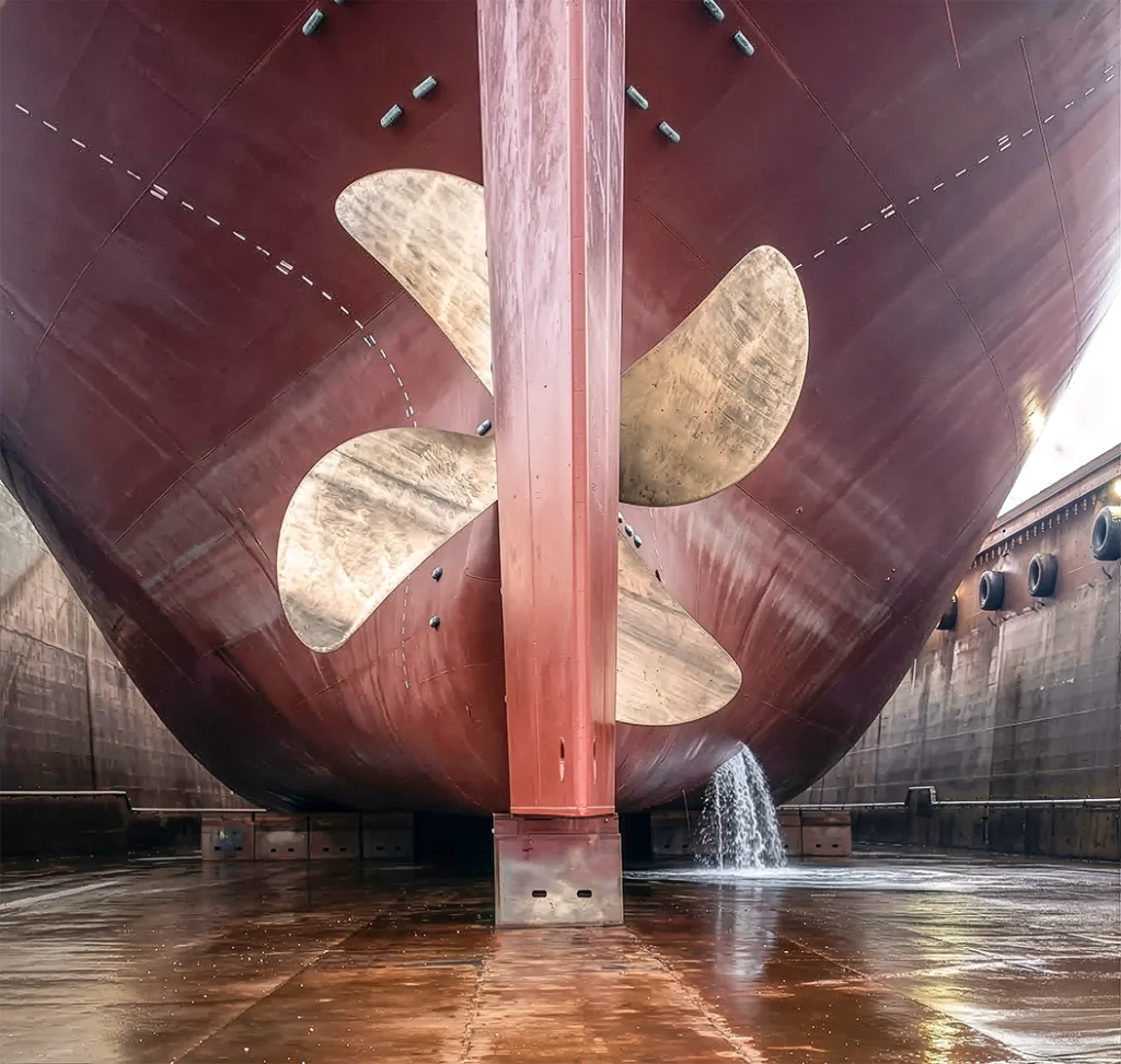 Large cargo ship stern and bronze propeller in a dry dock for maintenance at a Turkish shipyard.